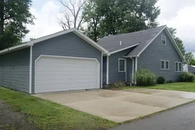 a blue house with a white garage at A spacious getaway on Orchard Island in Russells Point