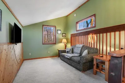 a living room with a chair and a television at Hot tub, fireplace, fire pit, pool table, grill, EV, pets, HOA lake in Amanda