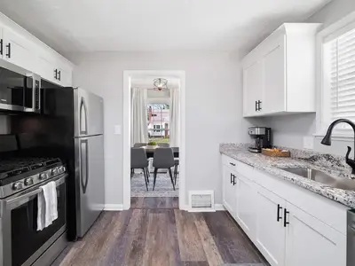 a kitchen with white cabinets and a black refrigerator at Home Away From Home - Beautiful Yard in South Euclid
