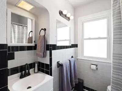 a white bathroom with a sink and a window at Home Away From Home - Beautiful Yard in South Euclid