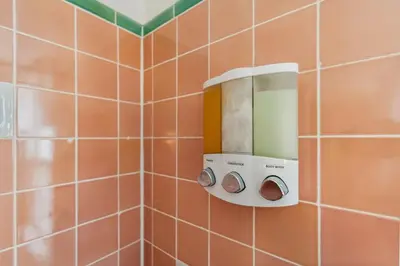 a tiled bathroom with a soap dispenser on a wall at Near CLE Clinic - Long term stays accepted in Shaker Heights
