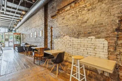 a brick wall in a restaurant with tables and chairs at The Victor 2 - Cleveland's Urban Lodge in Cleveland