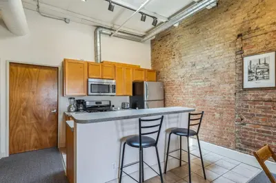 a kitchen with a counter and two stools at a bar at The Victor 3 - Cleveland's Urban Lodge in Cleveland