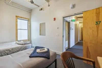 a room with two beds and a chair and a window at The Victor 3 - Cleveland's Urban Lodge in Cleveland