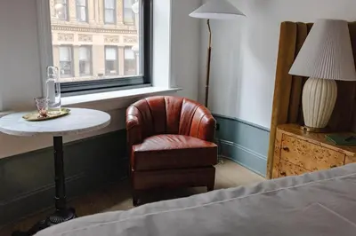 a bedroom with a chair and a table and a window at Fidelity Hotel in Cleveland