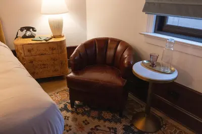a bedroom with a chair and a table and a lamp at Fidelity Hotel in Cleveland