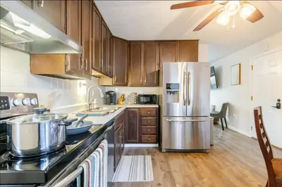 a kitchen with wooden cabinets and a stainless steel refrigerator at Private Ranch - Entire Home - 3 Bed Room - Hot Tub - King Bed - Fenced Yard - Pets & Kids Welcome - Game Shed - Free WiFi in Columbus