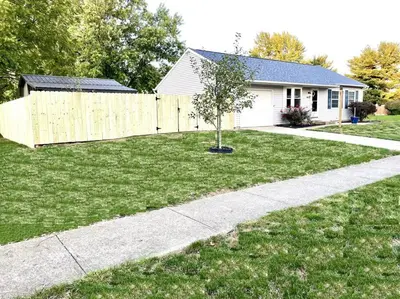 a house with a fence and a tree in a yard at Private Ranch - Entire Home - 3 Bed Room - Hot Tub - King Bed - Fenced Yard - Pets & Kids Welcome - Game Shed - Free WiFi in Columbus