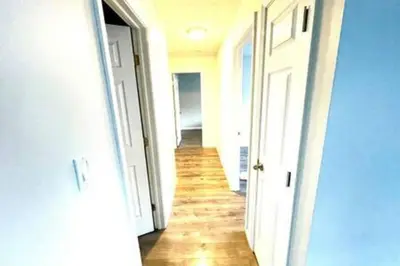 a hallway with white doors and a wooden floor at Private Ranch - Entire Home - 3 Bed Room - Hot Tub - King Bed - Fenced Yard - Pets & Kids Welcome - Game Shed - Free WiFi in Columbus