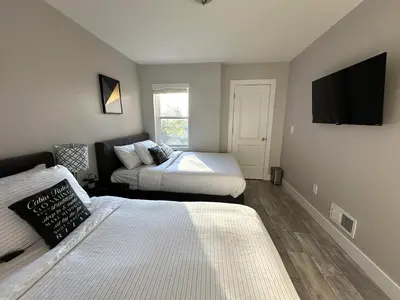 a bedroom with two beds and a tv on the wall at Charming 2BR Near Downtown & Attractions in Columbus