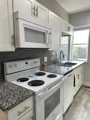 a white kitchen with a stove and a microwave at Charming 2BR Near Downtown & Attractions in Columbus