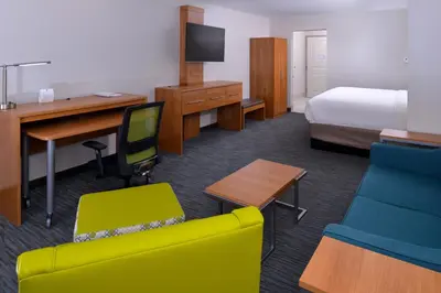 a hotel room with a bedroom with a bed and a desk at Holiday Inn Express & Suites Lexington Midtown - I-75 by IHG in Lexington