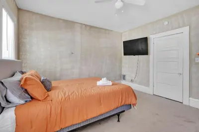 a bedroom with an orange bed and a tv on the wall at Cozy Renovated 19th Century Home, 5 Min to OSU! in Columbus