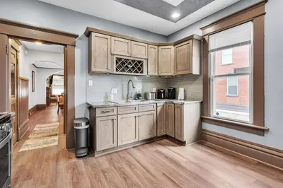 an empty kitchen with wooden cabinets and a window at Cozy Renovated 19th Century Home, 5 Min to OSU! in Columbus