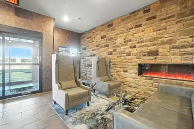 a living room with two chairs and a fireplace at Cobblestone Hotel & Suites - Bellefontaine in Bellefontaine