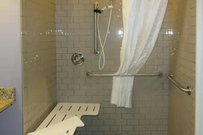 a shower with a bench and a shower curtain at Quality Inn & Suites Caldwell I-77 in Caldwell