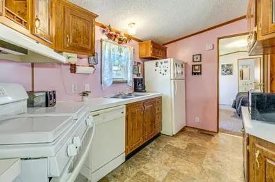 a kitchen with wooden cabinets and a white refrigerator at Paden City Home Near Ohio River! in New Martinsville
