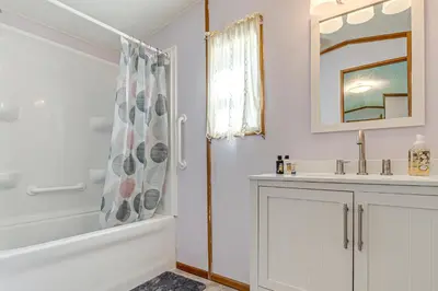a bathroom with a tub and a sink and a mirror at Paden City Home Near Ohio River! in New Martinsville