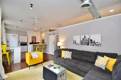 a living room with a black couch and a yellow chair at Walk to Everything - Sports, Food, Music, Downtown in Cincinnati