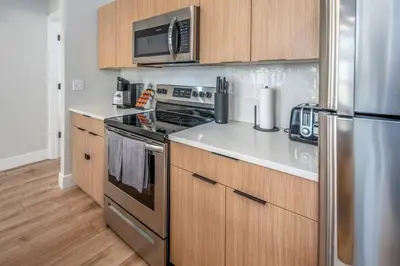 a kitchen with stainless steel appliances and wooden cabinets at Prime OTR, 1 Block to TQL, Cali King Bed, Sleeps 4ppl, Free Light Rail, Smart TVs in Over-The-Rhine