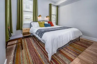 a bedroom with a bed with colorful pillows on it at Prime OTR, 1 Block to TQL, Cali King Bed, Sleeps 4ppl, Free Light Rail, Smart TVs in Over-The-Rhine