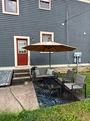 a table and chairs with an umbrella in front of a house at Eighty Three-Historic Downtown in Chillicothe