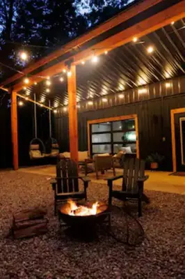 a patio with two chairs and a fire pit at night at The Hillside Retreat - Cozy container home with Hot tub and Fire pit in Logan