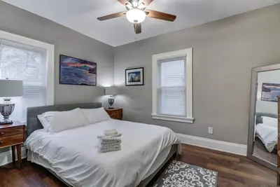 a bedroom with a white bed and a ceiling fan at The Gallery House - Art curated by local artist! in Cleveland Heights