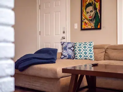 a living room with a brown couch and a table at The Gallery House - Art curated by local artist! in Cleveland Heights