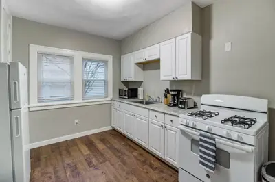 a kitchen with white cabinets and a white stove top oven at The Gallery House - Art curated by local artist! in Cleveland Heights