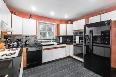 a kitchen with white cabinets and black appliances at Spacious Family Getaway - Near Cleveland Clinic in Cleveland