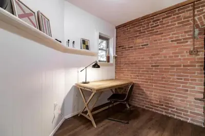 a room with a wooden desk next to a brick wall at Cute 1Bed Loft at The Foundry - Steps to Riverside in Cleveland