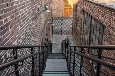 a stairway leading down to a brick building with a door at Cute 1Bed Loft at The Foundry - Steps to Riverside in Cleveland