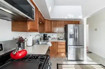 a kitchen with wooden cabinets and a stainless steel refrigerator at Cute 1Bed Loft at The Foundry - Steps to Riverside in Cleveland