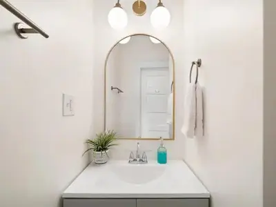 a white bathroom with a sink and a mirror at Newly Renovated - Professionally Designed - 2 BR in Lakewood