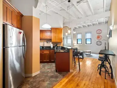 a kitchen with a stainless steel refrigerator and a table at Lakefront Loft - Walk 2 First Energy x Progressive in Cleveland