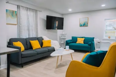 a living room with two blue couches and yellow pillows at Family Friendly Downtown Apple Creek by Antiques in Apple Creek