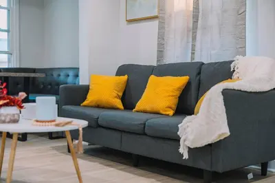 a living room with a blue couch with yellow pillows at Family Friendly Downtown Apple Creek by Antiques in Apple Creek