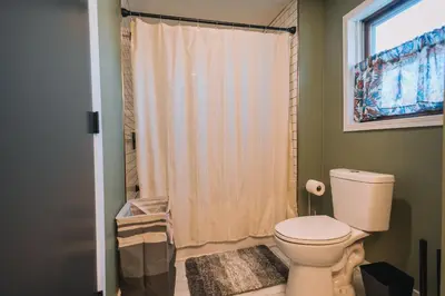 a bathroom with a toilet and a shower with a window at Family Friendly Downtown Apple Creek by Antiques in Apple Creek