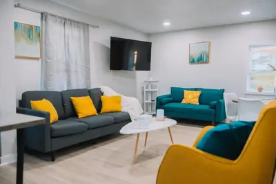 a living room with two blue couches and yellow pillows at Family Friendly Downtown Apple Creek by Antiques in Apple Creek