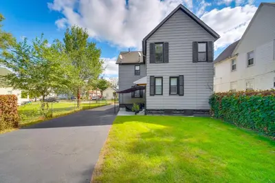 a white house with a grass yard in front of it at 4 Mi to Dtwn Home with Patio in Cleveland! in Cleveland