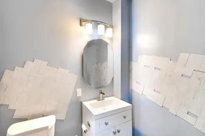 a white bathroom with a sink and a mirror at 4 Mi to Dtwn Home with Patio in Cleveland! in Cleveland
