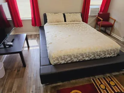 a bedroom with a bed and a desk and red curtains at Comfy 1BR Apt. in Pleasant Ridge in Cincinnati