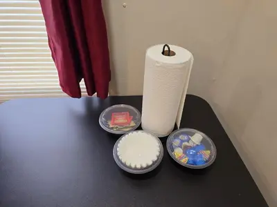 a table with a roll of toilet paper and some plates at Cozy 1BR in Pleasant Ridge in Cincinnati