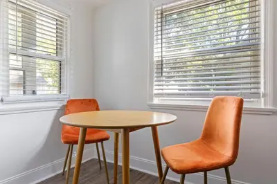 two chairs and a table in a room with two windows at Family Friendly 3BR with Sunroom and Outdoor Area in Maple Heights