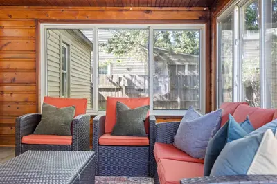 a porch with a couch and chairs and windows at Family Friendly 3BR with Sunroom and Outdoor Area in Maple Heights