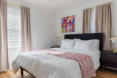 a bedroom with a large bed with white sheets at Family Friendly 3BR with Sunroom and Outdoor Area in Maple Heights
