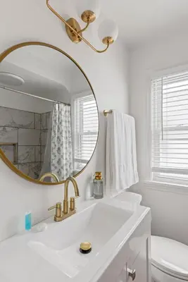 a white bathroom with a gold mirror and a sink at 27150 Forestview Ave, Euclid in Euclid