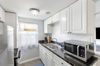 a white kitchen with a sink and a microwave at Heights Dream Libby Unit 6 in Maple Heights