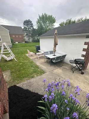 a patio with a bench and a umbrella and flowers at Akron Abode - 2pm Check In & Out in Akron